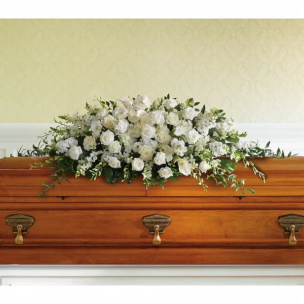 Wooden coffin adorned with decorative floral arrangement on plain background