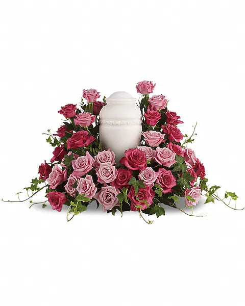 White urn surrounded by pink and red roses