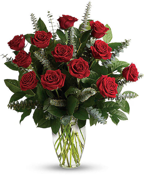 Bouquet of fresh red roses with green leaves in a clear vase