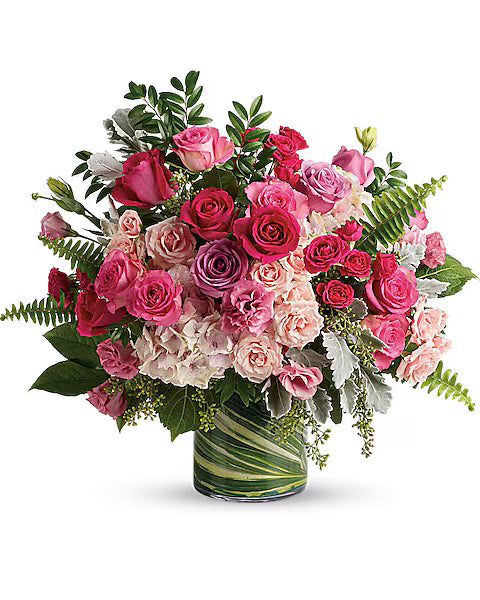 Bouquet of Bright pink and red roses with greenery in a clear vase