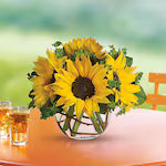 Bouquet of sunflowers in a clear vase on a table with a blurred background