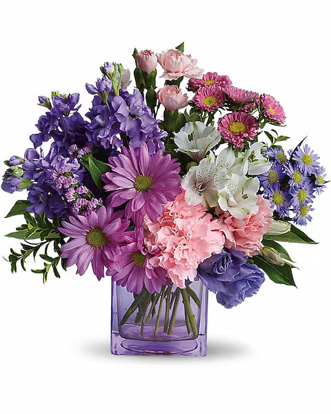 Fresh mixed flowers in transparent vase with purple, pink, and white blooms