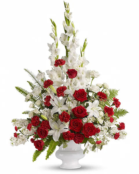 White vase containing red and white floral arrangement on white background