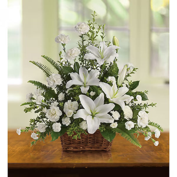 White lilies and assorted flowers elegantly arranged in basket on wood surface