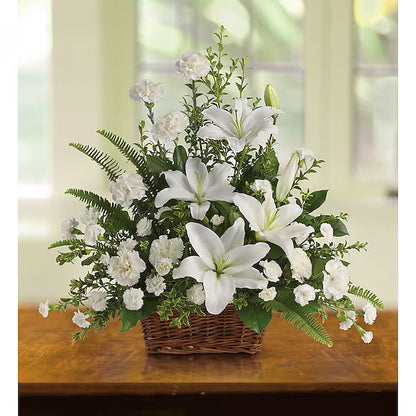 White lilies and assorted flowers elegantly arranged in basket on wood surface