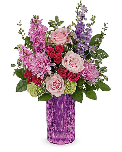 Colorful flower arrangement in a purple vase on a white background