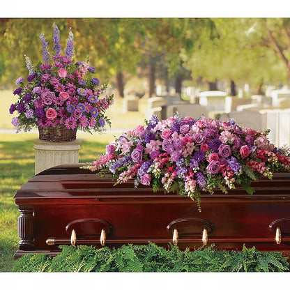 Casket adorned with floral arrangement in a cemetery setting