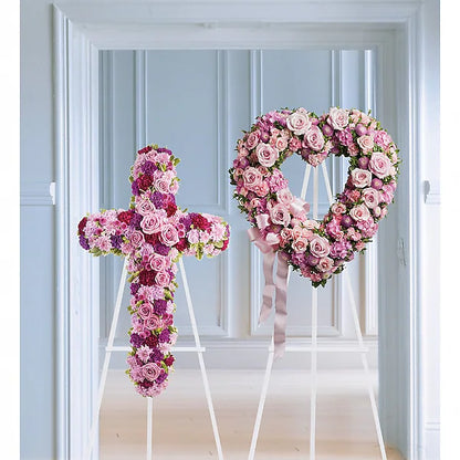 Colorful floral cross and heart arrangements on stands in front of blue wall
