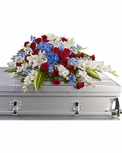 Casket with a floral arrangement of red, white, and blue flowers on a white background
