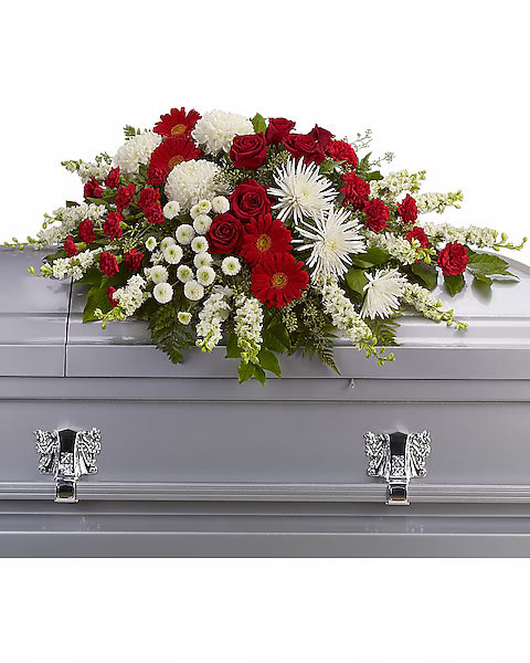Gray coffin topped with red and white blooms