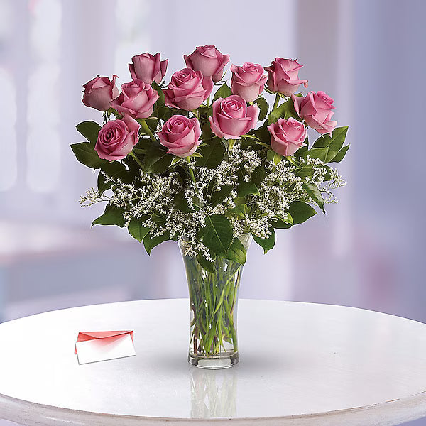 Bouquet of pink roses in a clear vase on a white surface with a blurred background