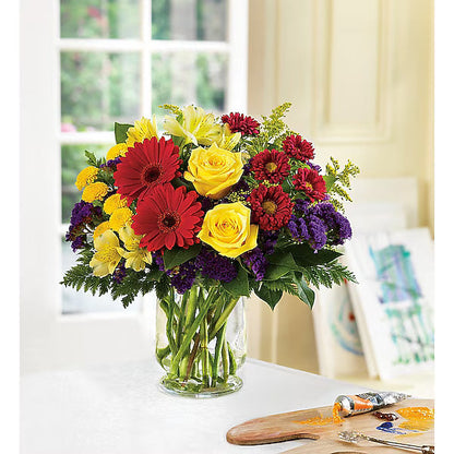 Vibrant bouquet of assorted flowers in a clear vase on a table
