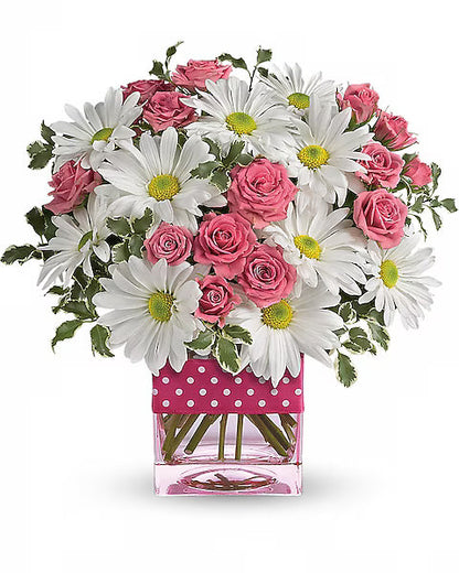 Pink roses and white daisies in a clear vase with pink polka dots.