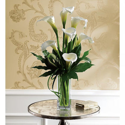Bouquet of white calla lilies in a clear vase on a round table