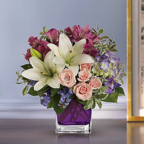 Elegant bouquet of white lilies, pink roses, and purple hydrangeas arranged in a glossy purple