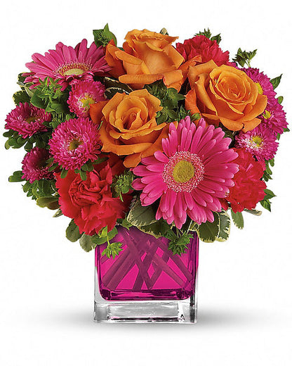 Colorful flower arrangement with pink, orange, and red flowers in a pink vase on a white background
