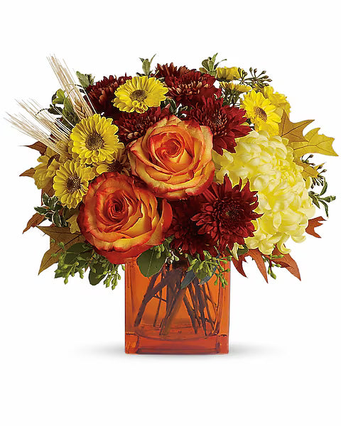Autumn-themed flower arrangement with roses, daisies, and hydrangeas in a clear vase